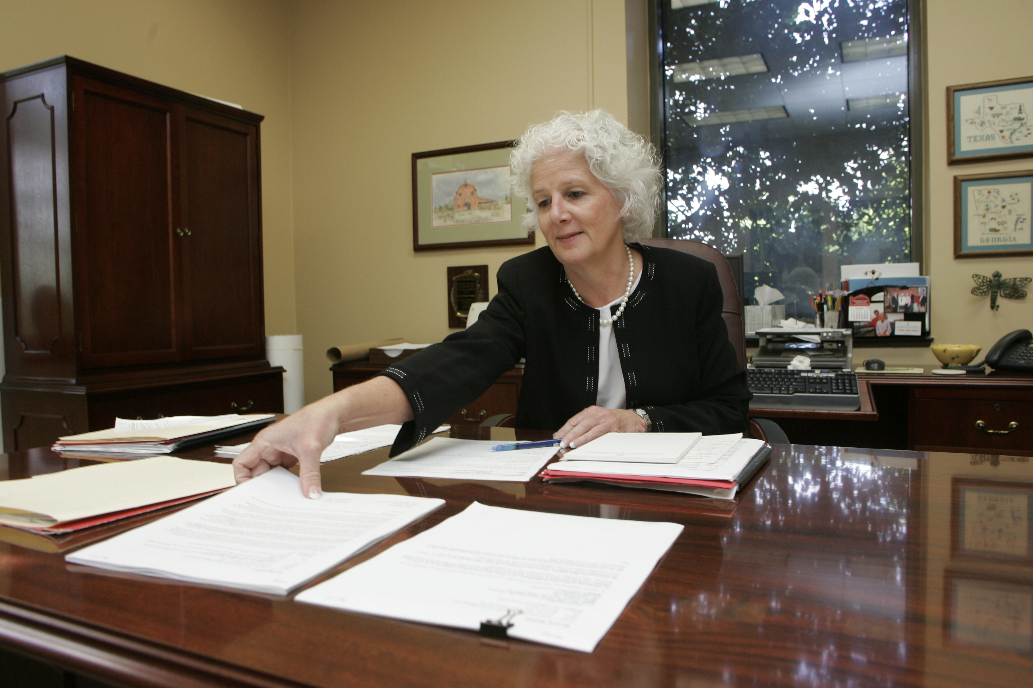 Beverly Sparks sits at a desk reaching for a stack of papers